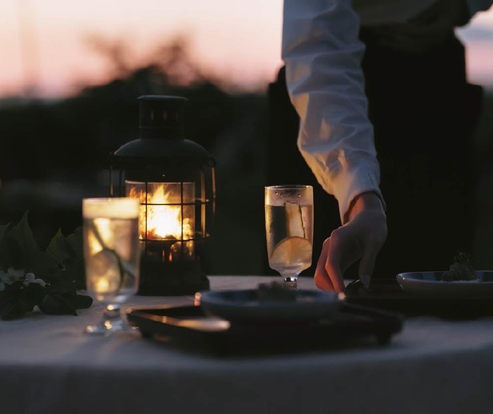 A dish being served to the table at dusk